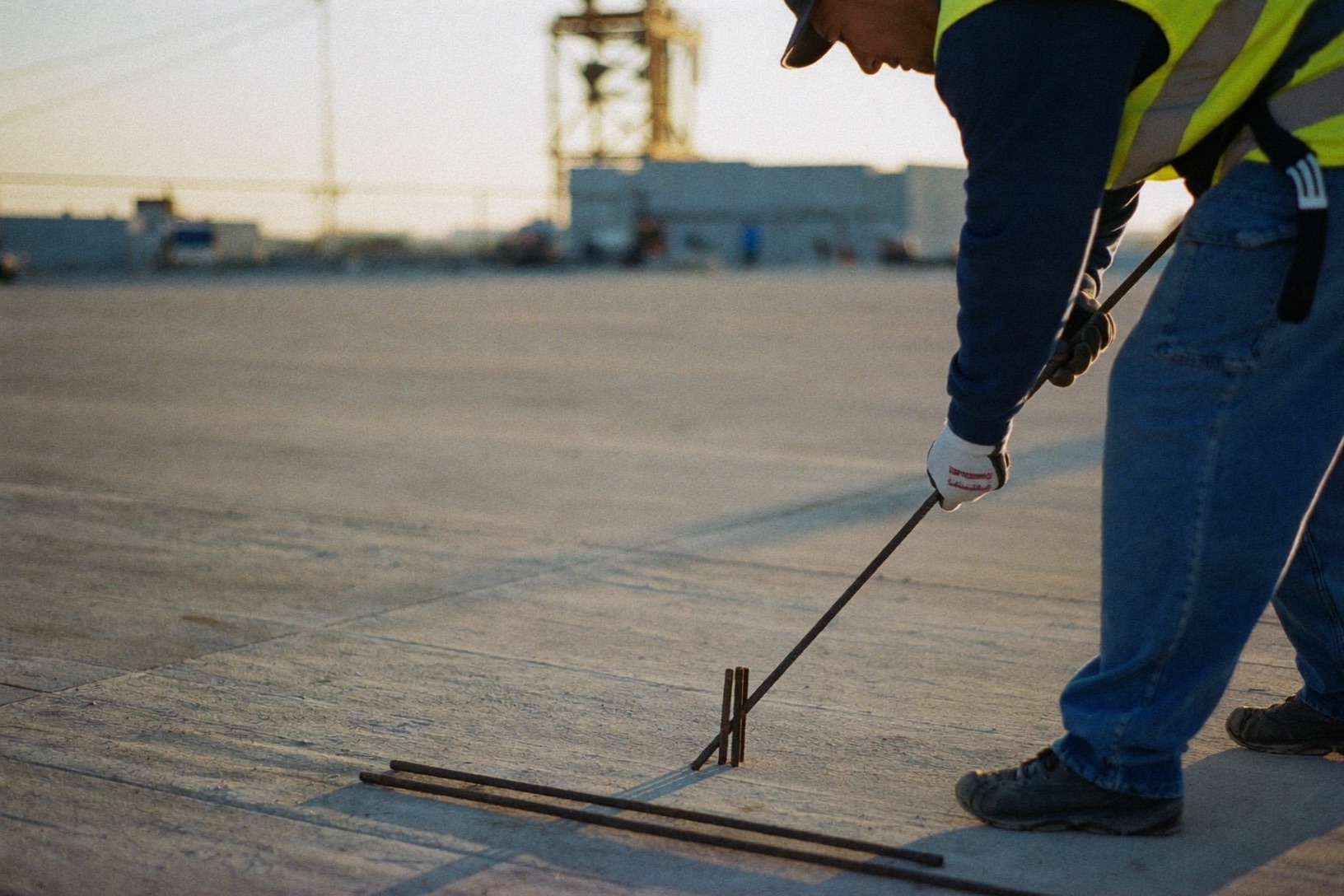 Worker placing rebar on a concrete deck at golden hour