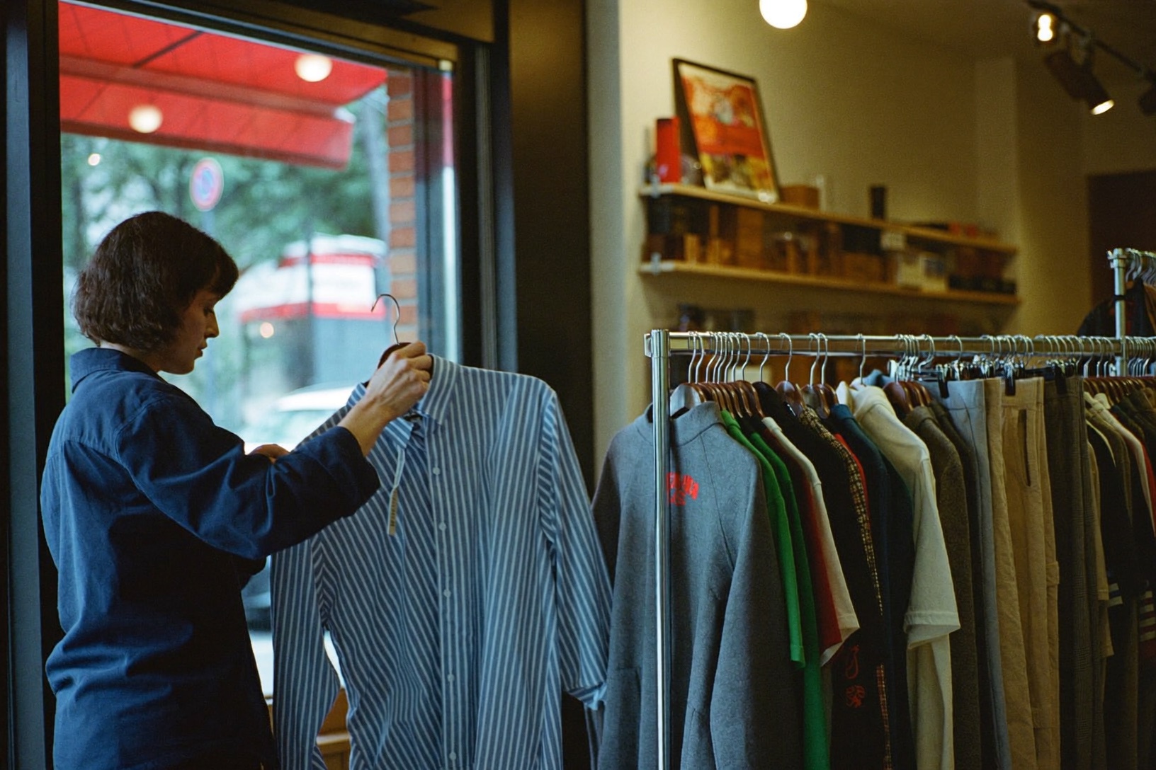Owner checking a shirt beside open racks in her independent clothing shop